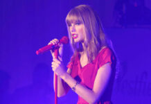 Taylor Swift in a red dress performing on stage.