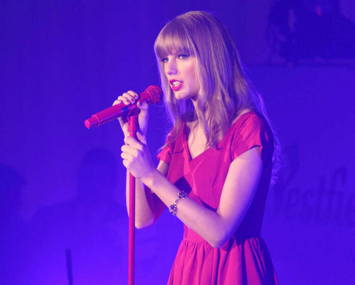 shutterstock_147305117.jpg Taylor Swift in a red dress performing on stage.