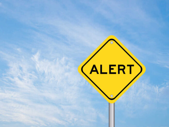 shutterstock_1668762586.jpg Yellow alert sign against a blue sky
