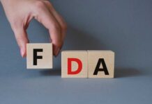 A hand holding a wooden block with the letter F, next to blocks spelling FDA