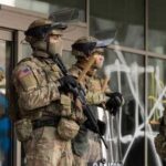 Military personnel in tactical gear standing guard during a protest