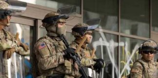 Military personnel in tactical gear standing guard during a protest