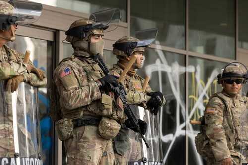 Military personnel in tactical gear standing guard during a protest