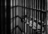 Black and white prison cell bars in dim light.