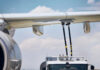 Close-up of an airplane wing being fueled by a ground support truck
