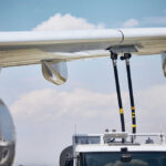 Close-up of an airplane wing being fueled by a ground support truck