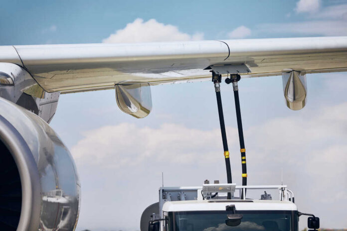 Close-up of an airplane wing being fueled by a ground support truck