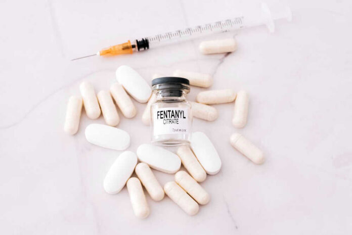 Fentanyl citrate vial surrounded by various pills and syringe.