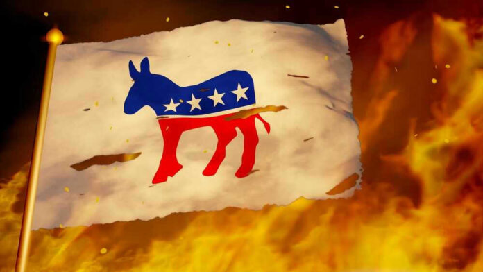 Torn Democratic flag burning amid flames and embers.