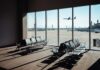 View of an airport waiting area with an airplane taking off in the background