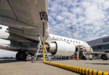 An airplane being fueled at an airport with a visible jet engine