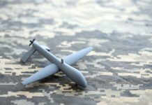 A gray drone model placed on a camouflage patterned surface