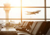 View of an airport terminal with an airplane taking off in the background