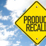 Yellow product recall sign against cloudy sky