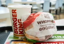 A Whopper Jr. burger wrapped in paper next to a Burger King drink
