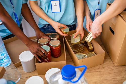 Volunteers organizing canned goods and jars for a food donation
