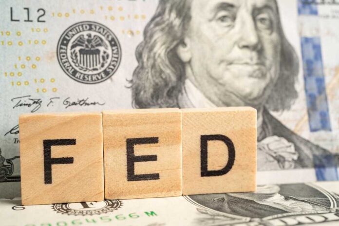 Wooden blocks spelling 'FED' in front of a hundred dollar bill