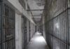 Empty prison corridor with barred cells on either side