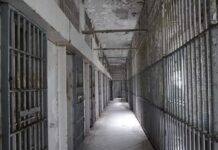 Empty prison corridor with barred cells on either side