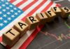 Wooden blocks spelling 'TARIFFS' on a background of the US flag and financial charts