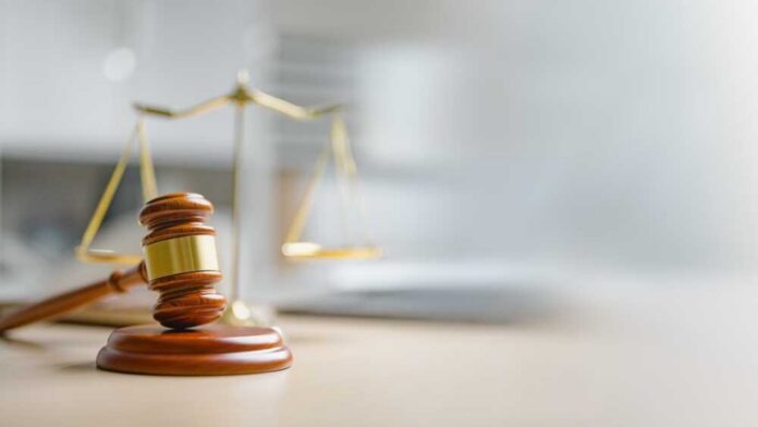 A wooden gavel and scales of justice on a desk
