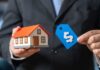 A person in a suit holding a miniature house and a price tag
