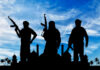 Silhouetted figures holding weapons against a blue sky