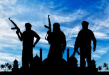 Silhouetted figures holding weapons against a blue sky