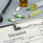 Medical supplies including a stethoscope, syringes, and medication related to measles