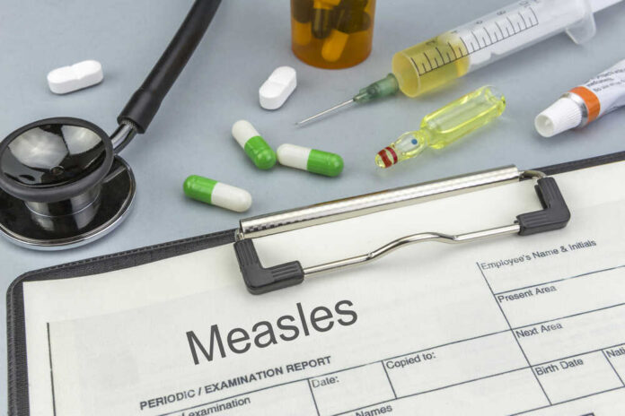 Medical supplies including a stethoscope, syringes, and medication related to measles