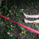 Bare feet visible near caution tape in a wooded area