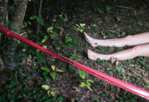 Bare feet visible near caution tape in a wooded area
