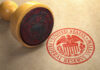 A wooden stamp with the Federal Reserve seal on a brown paper background