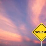 A yellow warning sign with the word 'SCHEME' against a colorful sky