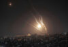 Night sky with rockets launching over a city.