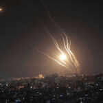 Night sky with rockets launching over a city.
