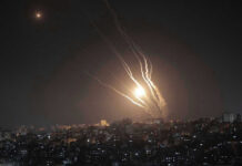 Night sky with rockets launching over a city.