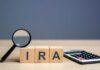 Magnifying glass and wooden blocks spelling 'IRA' next to a calculator