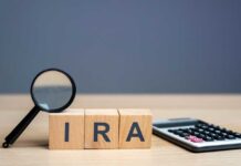 Magnifying glass and wooden blocks spelling 'IRA' next to a calculator