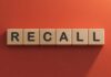 The word 'RECALL' displayed in wooden letter blocks against a red background