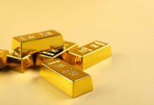 Several gold bars stacked on a golden surface