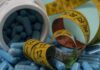Blue capsules spilled from a white bottle alongside measuring tapes