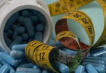 Blue capsules spilled from a white bottle alongside measuring tapes