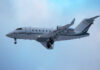 A private jet approaching for landing against a cloudy sky
