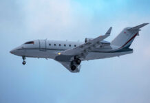 A private jet approaching for landing against a cloudy sky