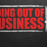 A hand writing 'GOING OUT OF BUSINESS' on a chalkboard