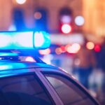 Close-up of a police car with blue emergency lights in a city at night