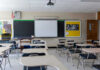 Empty classroom with desks, projector, and chalkboard.