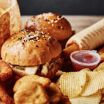 A variety of fast food items including burgers, onion rings, and chips