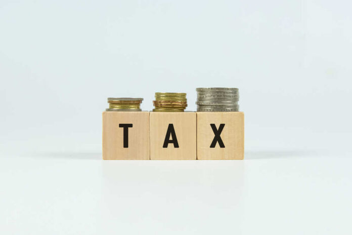 Blocks spelling 'TAX' with coins stacked beside them